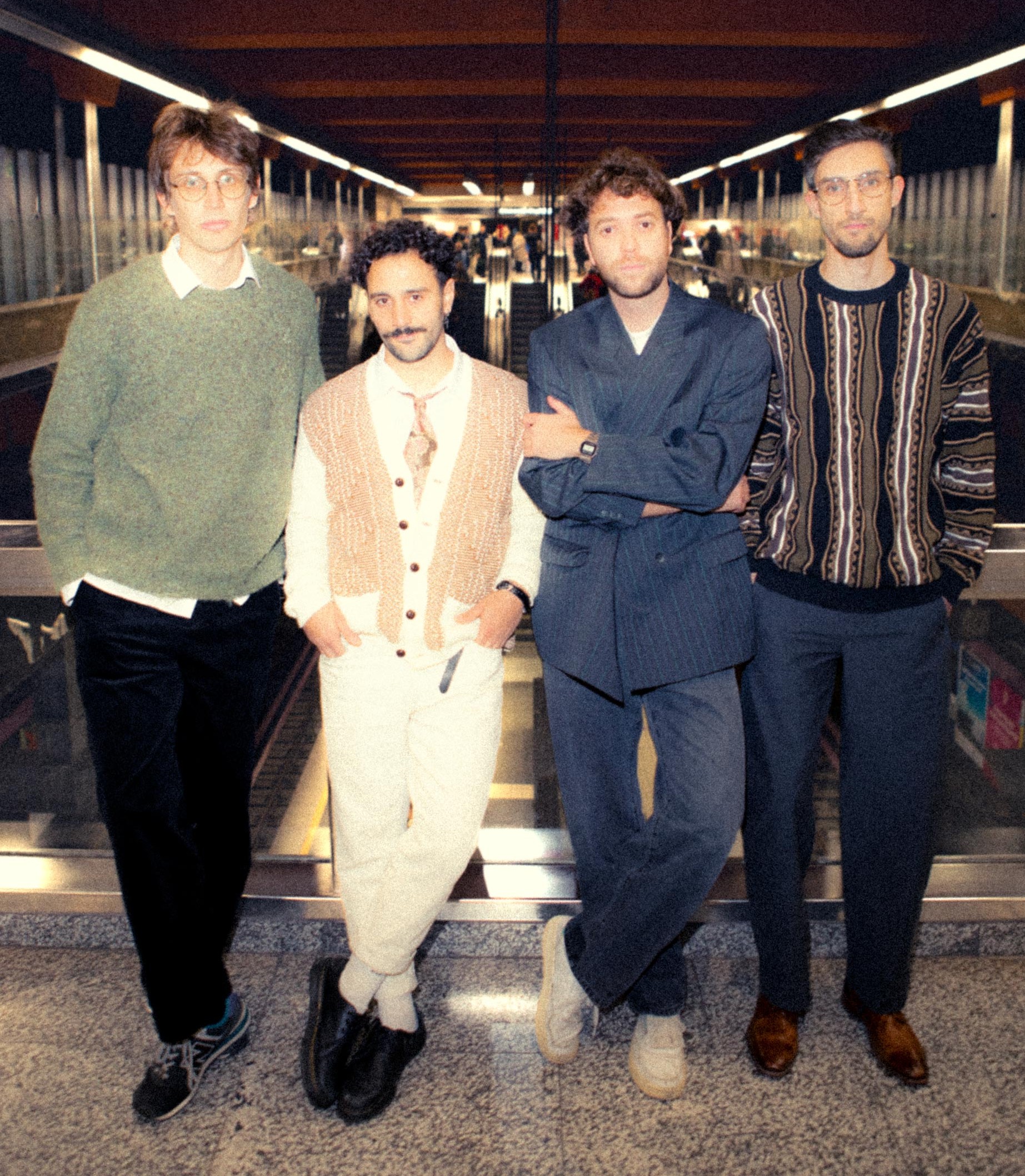 Siamese Elephants, four band members standing on an escalator platform